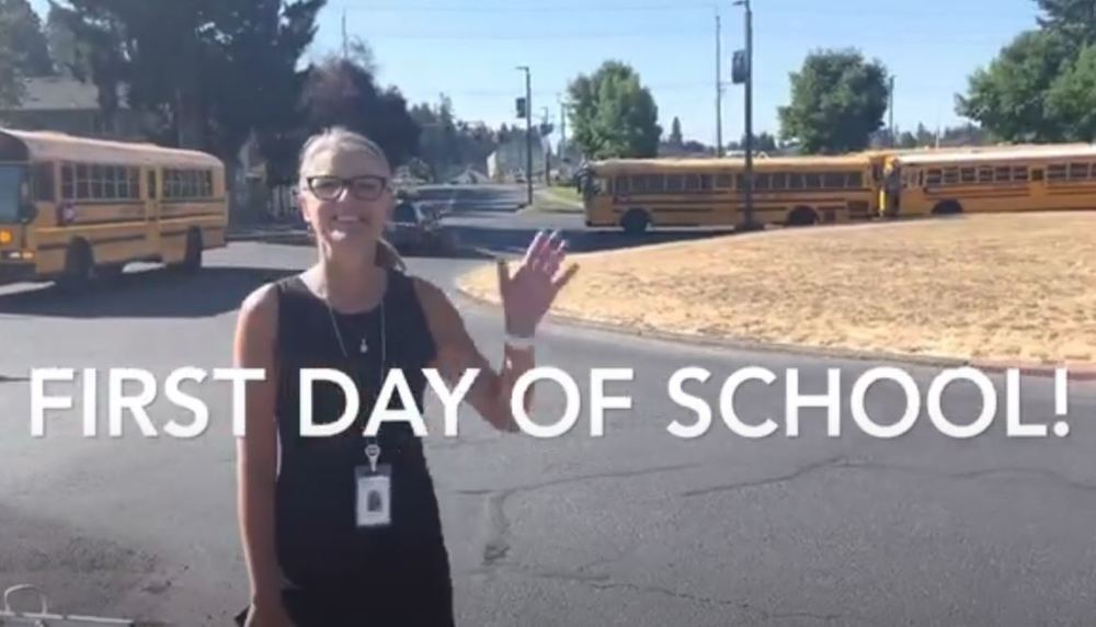 First day of school text over a picture of the director with buses in the background