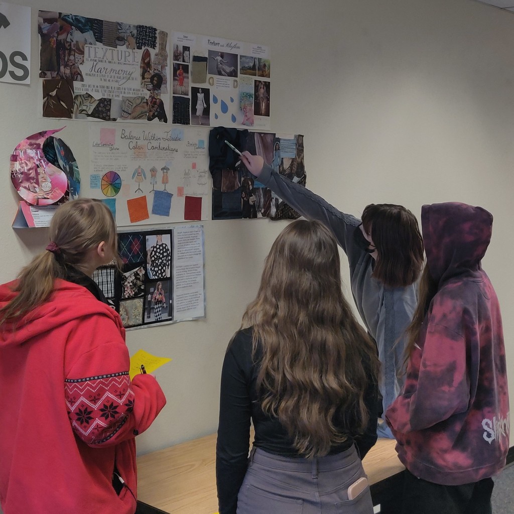 Students looking at projects on wall.