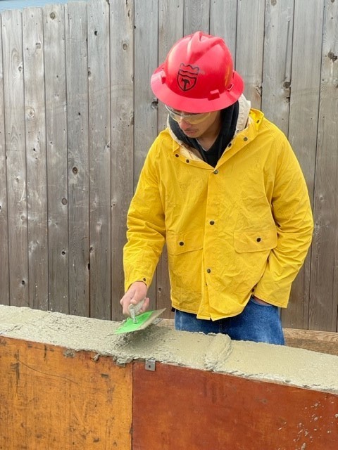 Student using trowel to smooth the concrete